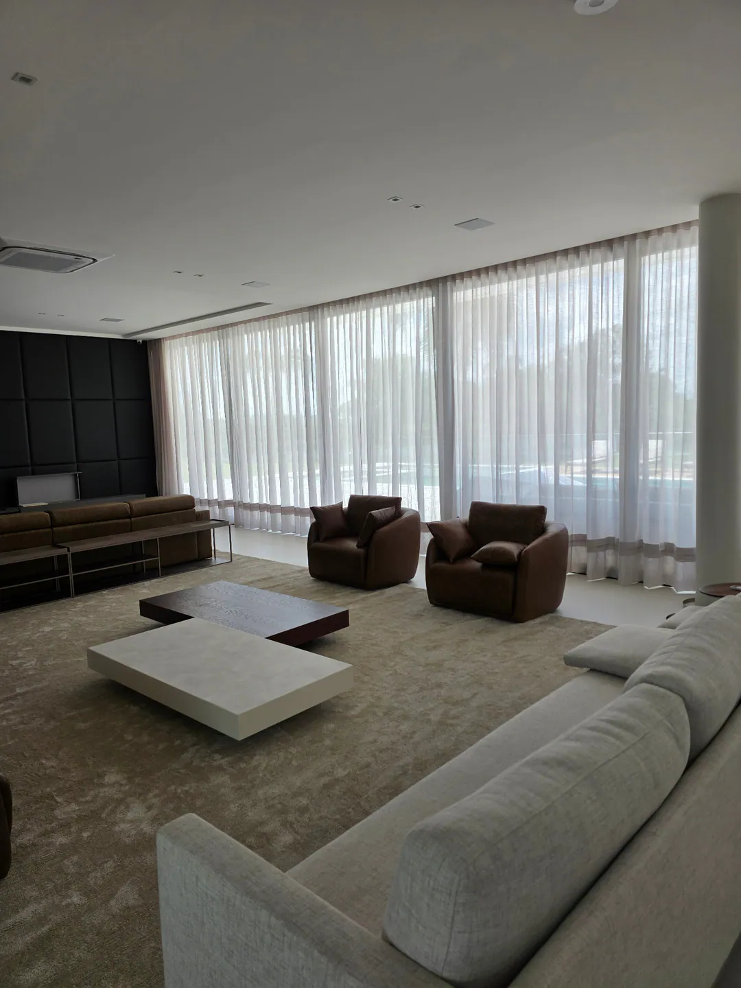 Cortinas leves ao redor de uma sala de estar ampla